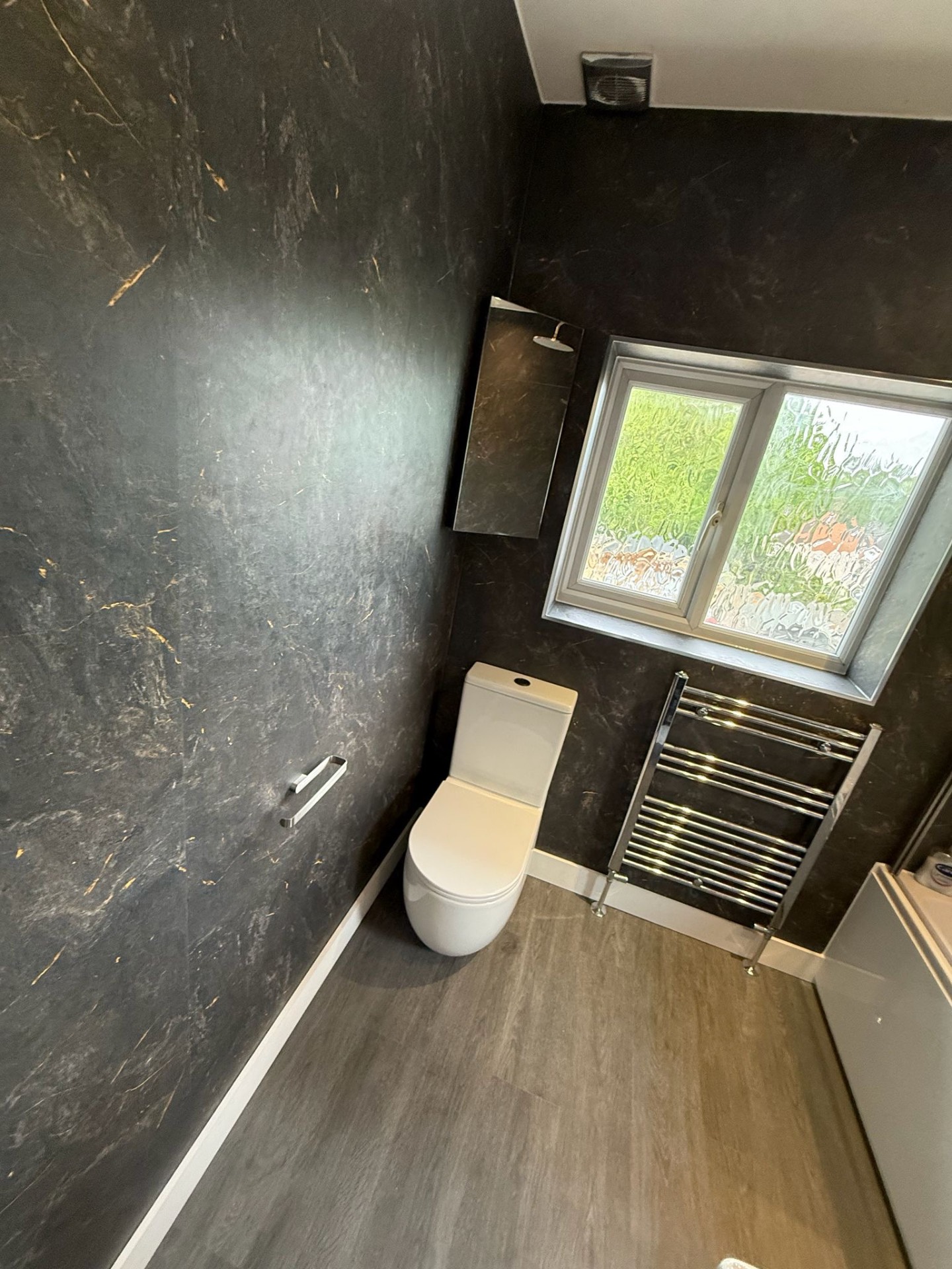 Dark marble cloakroom with chrome heated towel rail