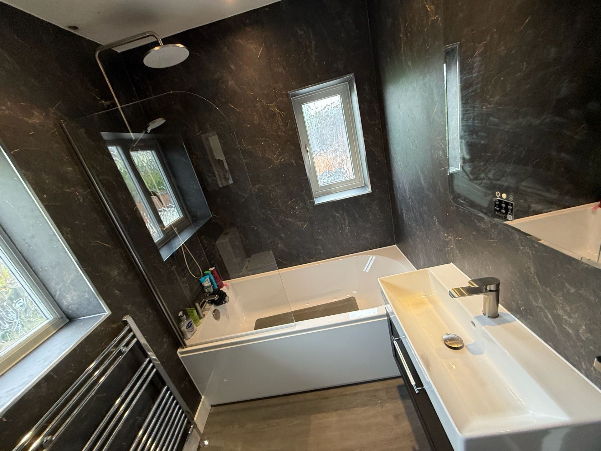 Dark marble-effect bathroom with bath, vanity and mirrored wall cabinet