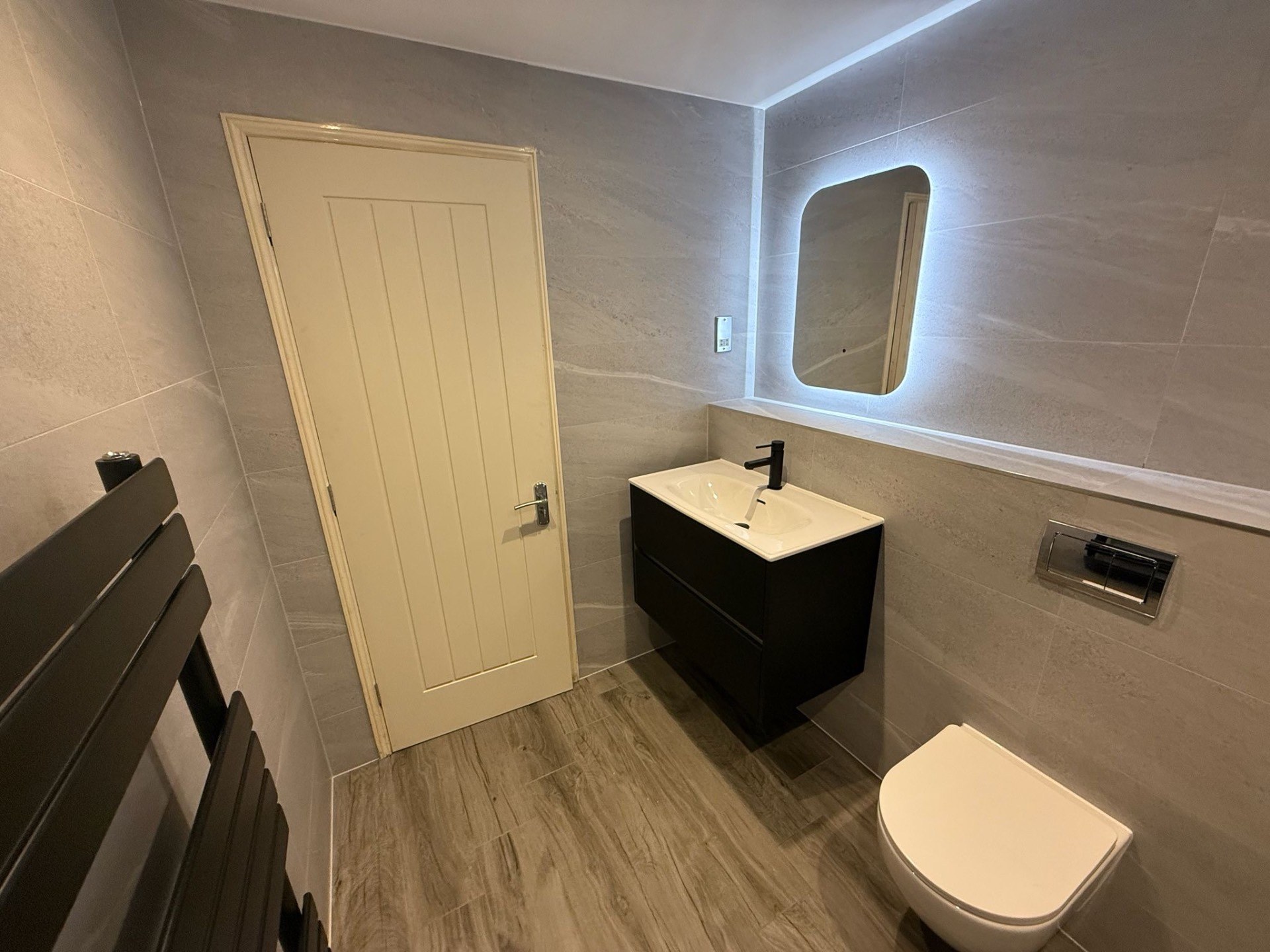 Contemporary bathroom with backlit mirror and wall-hung vanity