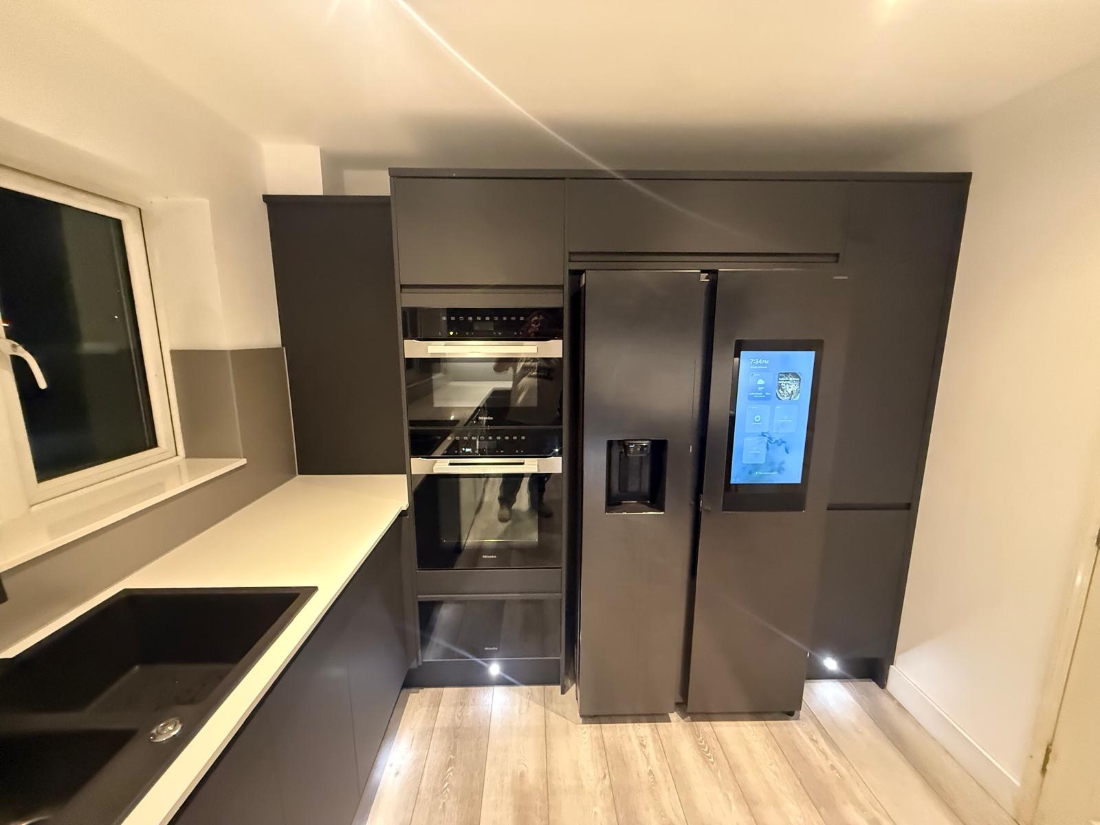 Dark fitted kitchen with integrated fridge and ovens