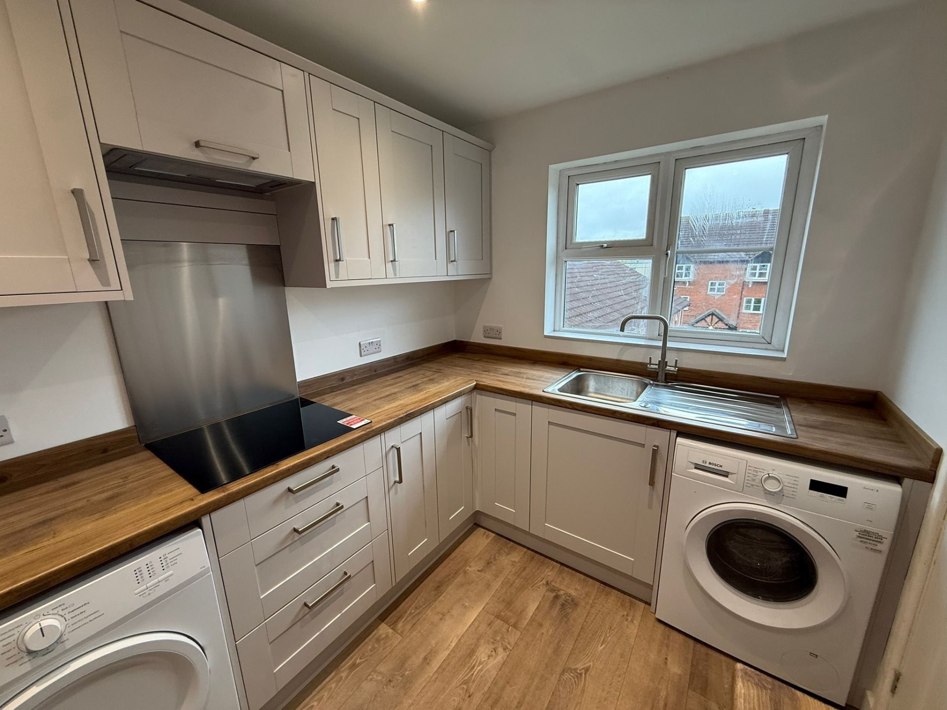Compact white Shaker kitchen with timber worktops and integrated laundry