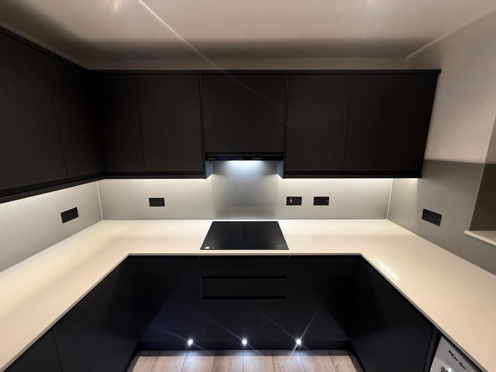 Dark fitted kitchen with seamless worktops and under-cabinet lighting